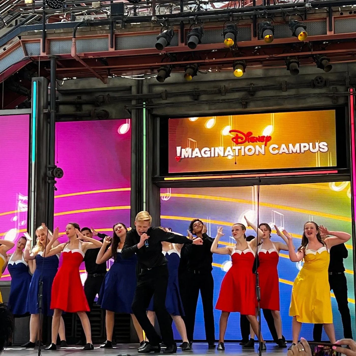The full Aspire company performing beneath the Disney Imagination Campus marquee