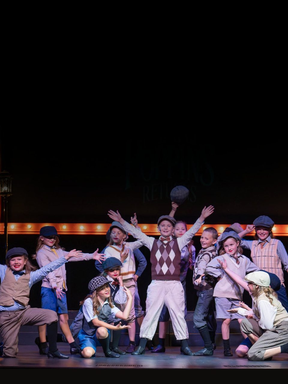 Young Aspire performers in newsboy costumes in Mary Poppins Returns