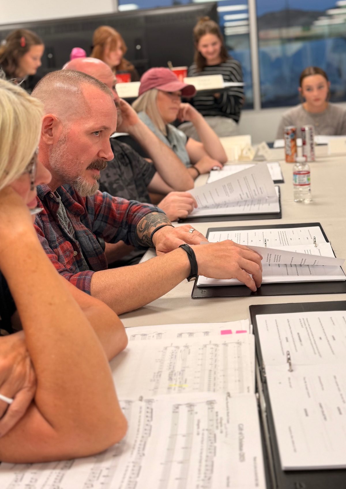 A member of the company following along in the script with the score open on the table