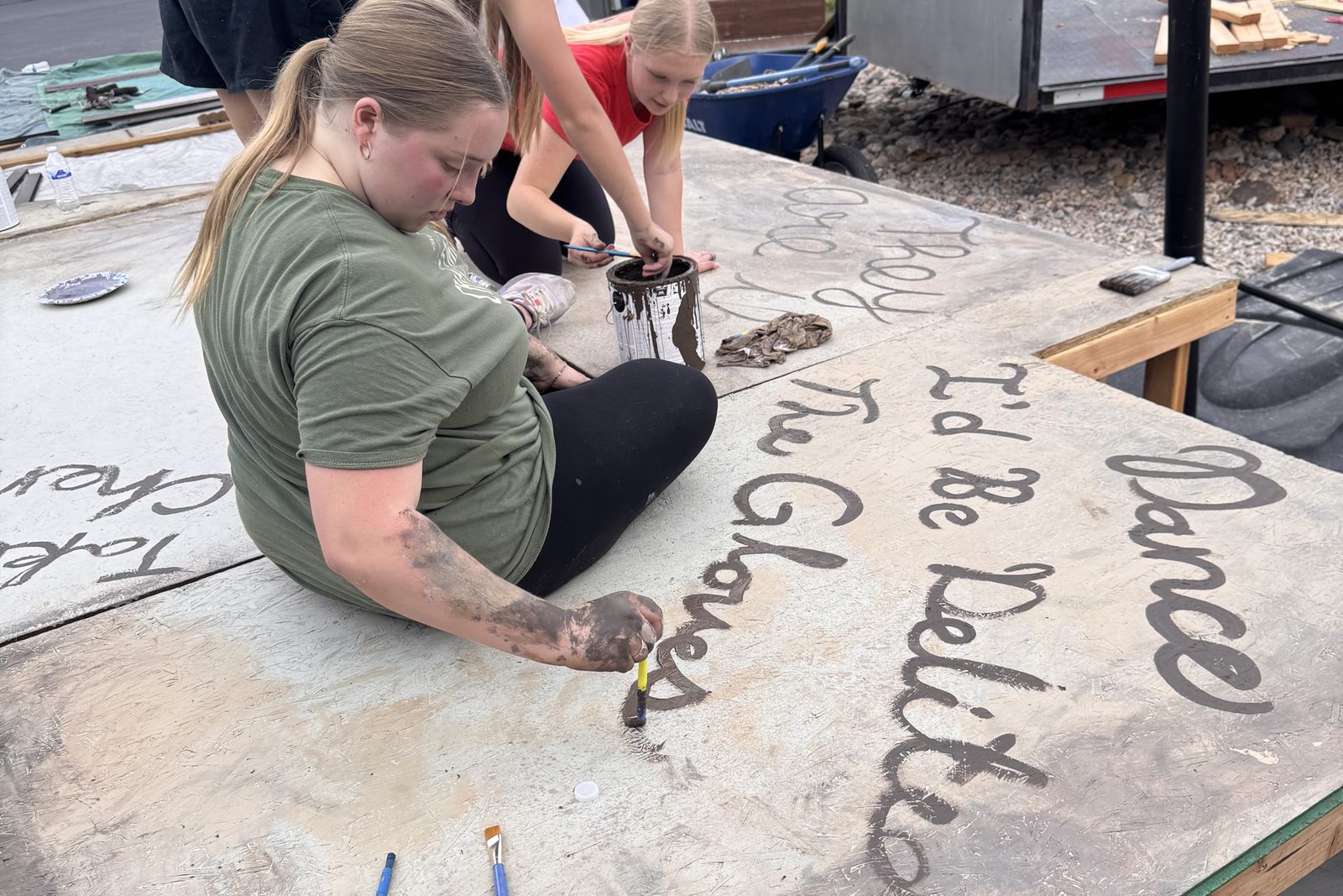 Young Artists painting lettering onto a set flat for Little Women