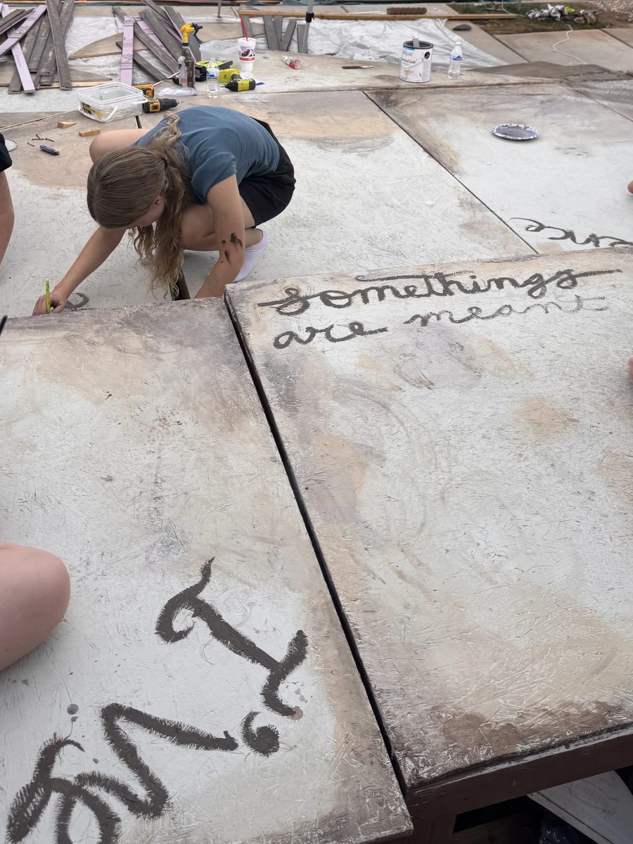 Young Artists painting lettering across two set flats