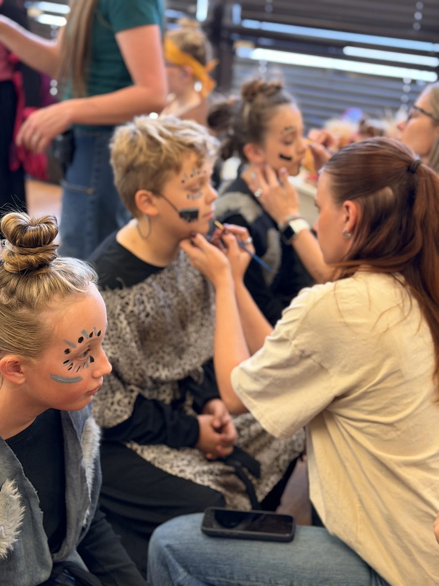 Volunteers paint hyena makeup on a group of Young Artists
