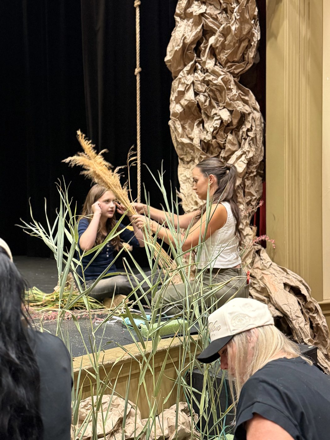 Volunteers dress the set with grasses beneath the paper-bark tree