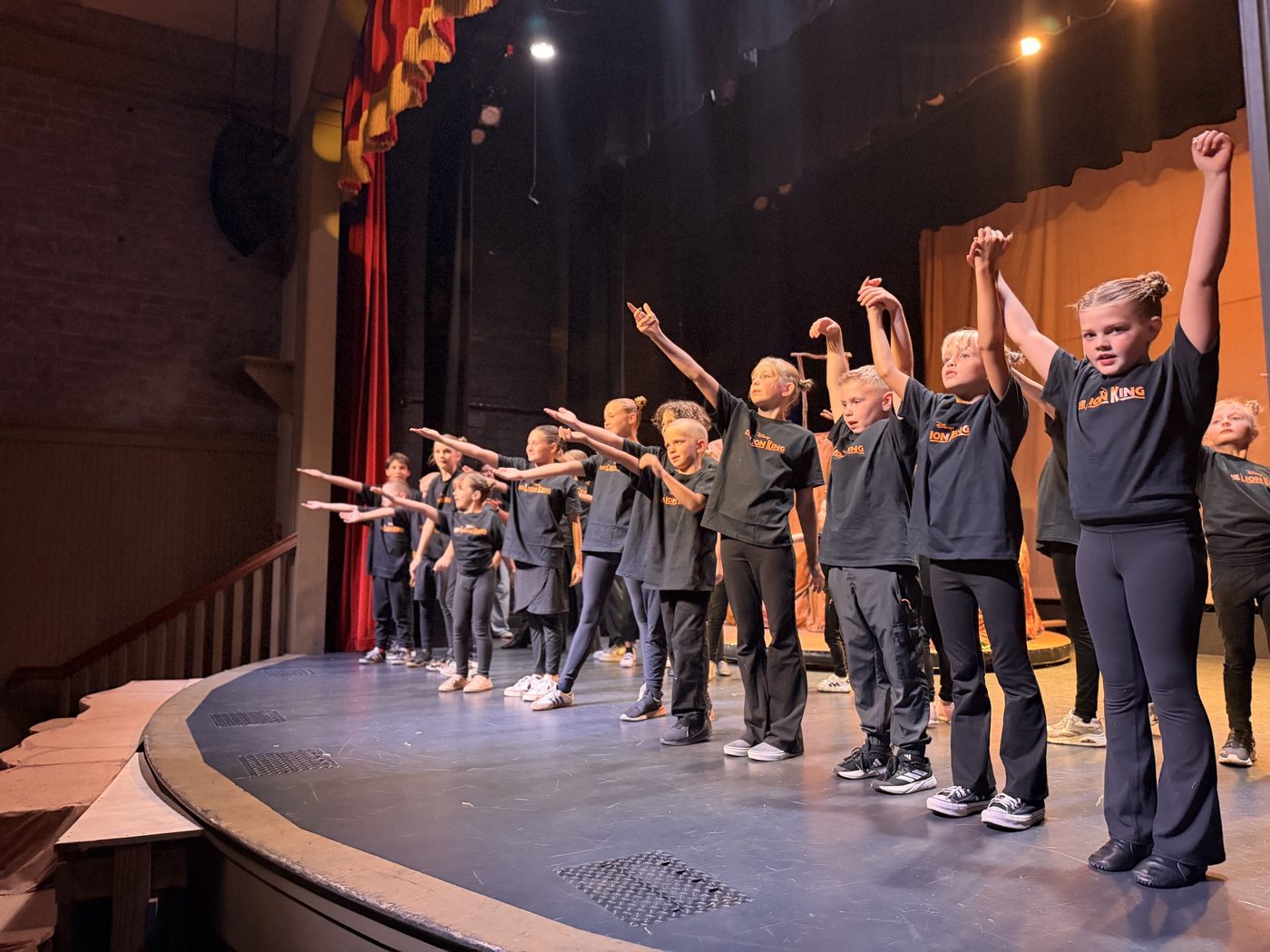 Young Artists reach their arms overhead during a Lion King Kids Camp number