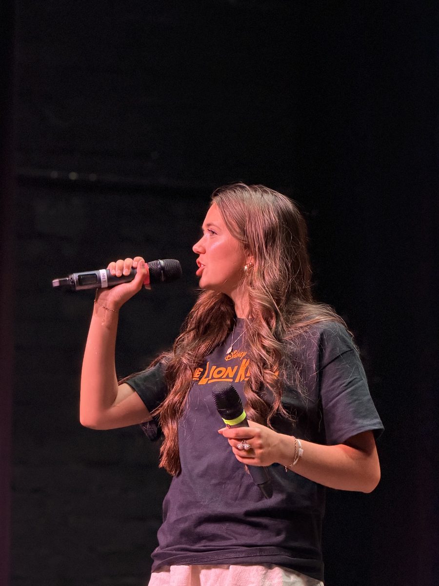 A camp leader addressing the company from the stage