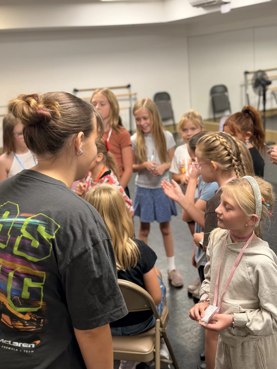 A youth leader talking with campers in the rehearsal room