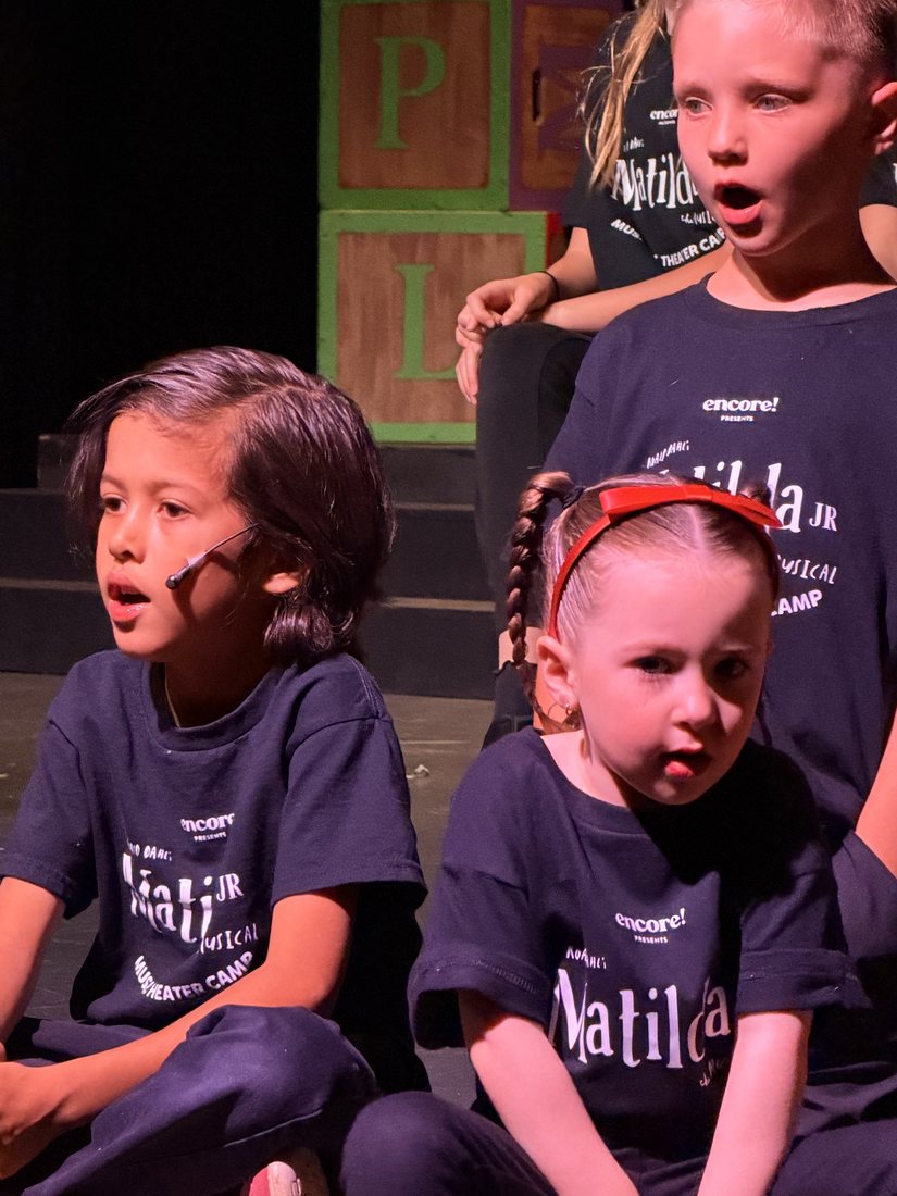 Two young performers in camp shirts on stage