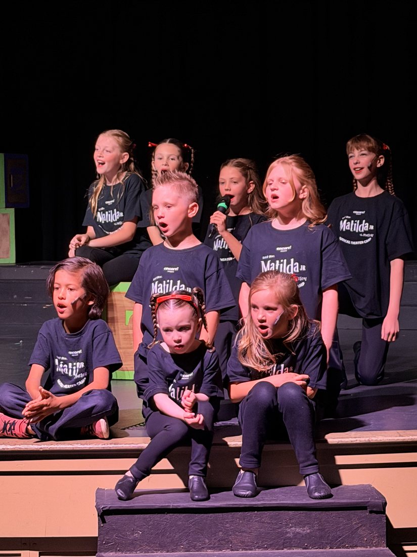 Young Artists in camp shirts performing on stage steps